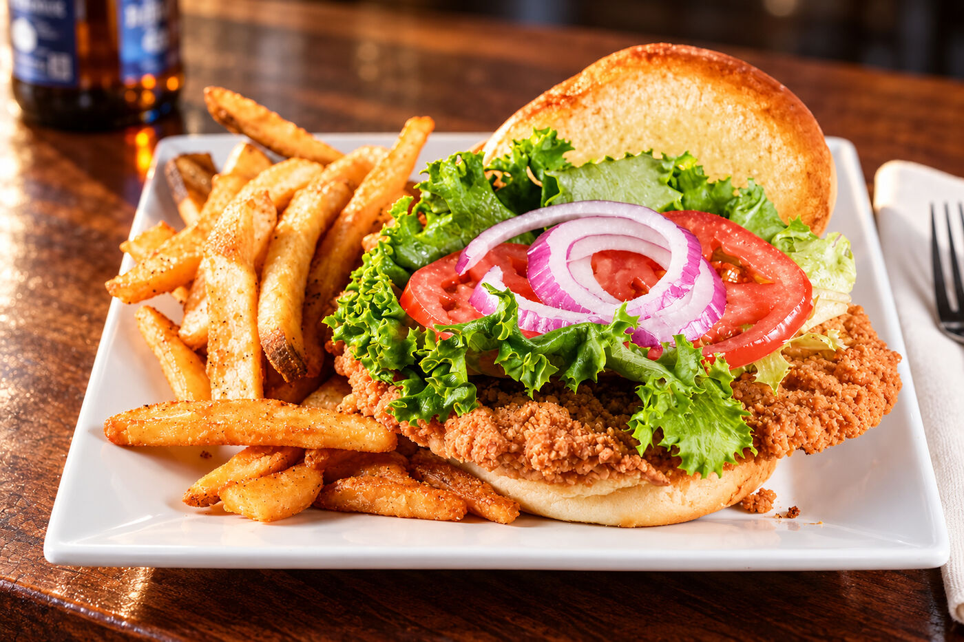 Breaded pork tenderloin sandwich, wider than the bun, with fries