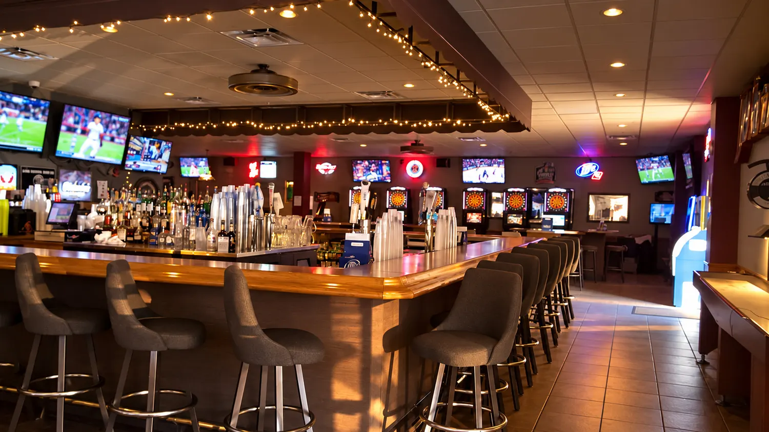 The long bar at Bojak's under a row of TVs, string lights along the ceiling